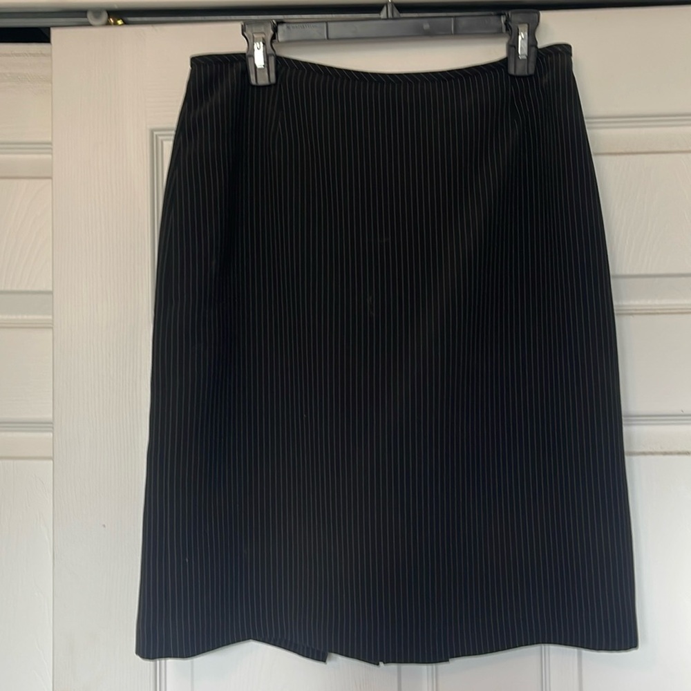 Black pinstriped pencil skirt. Pleated detail around slit in the back.